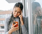 Kobieta patrzy na swój smartfon z poważnym wyrazem twarzy